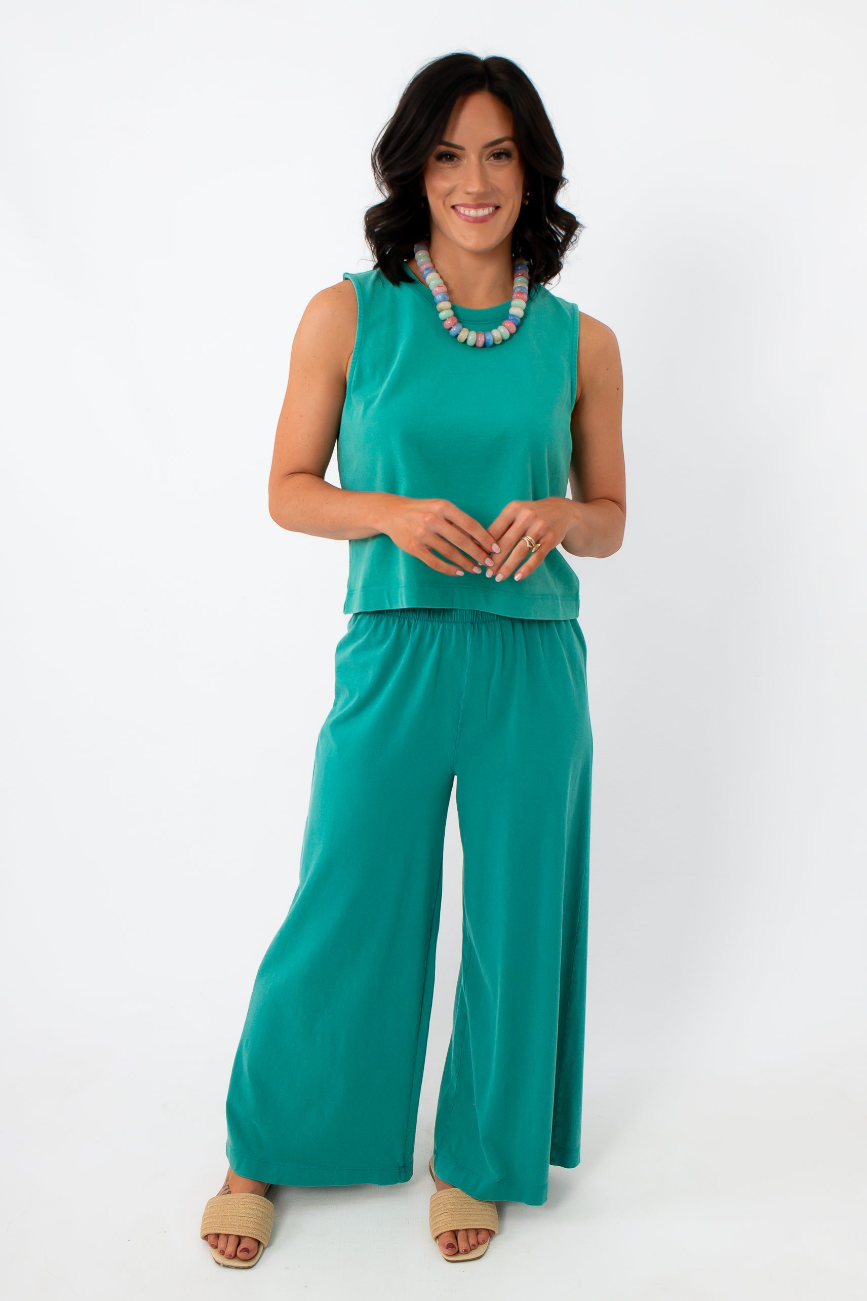 Women wearing bright teal sleeveless top with wide-leg pants, summer outfit