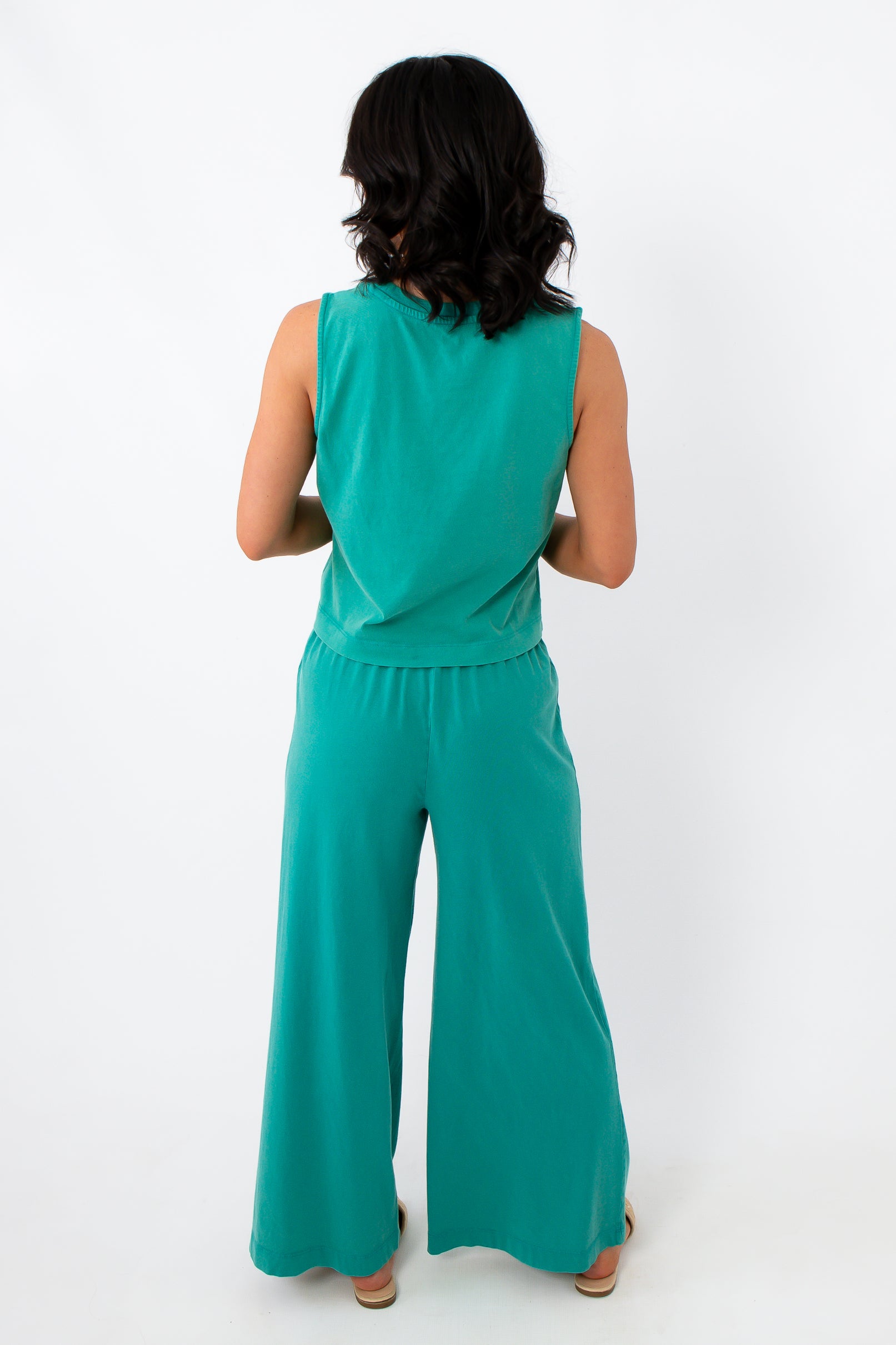 Side view of women in teal lounge set with relaxed fit and beige slide sandals