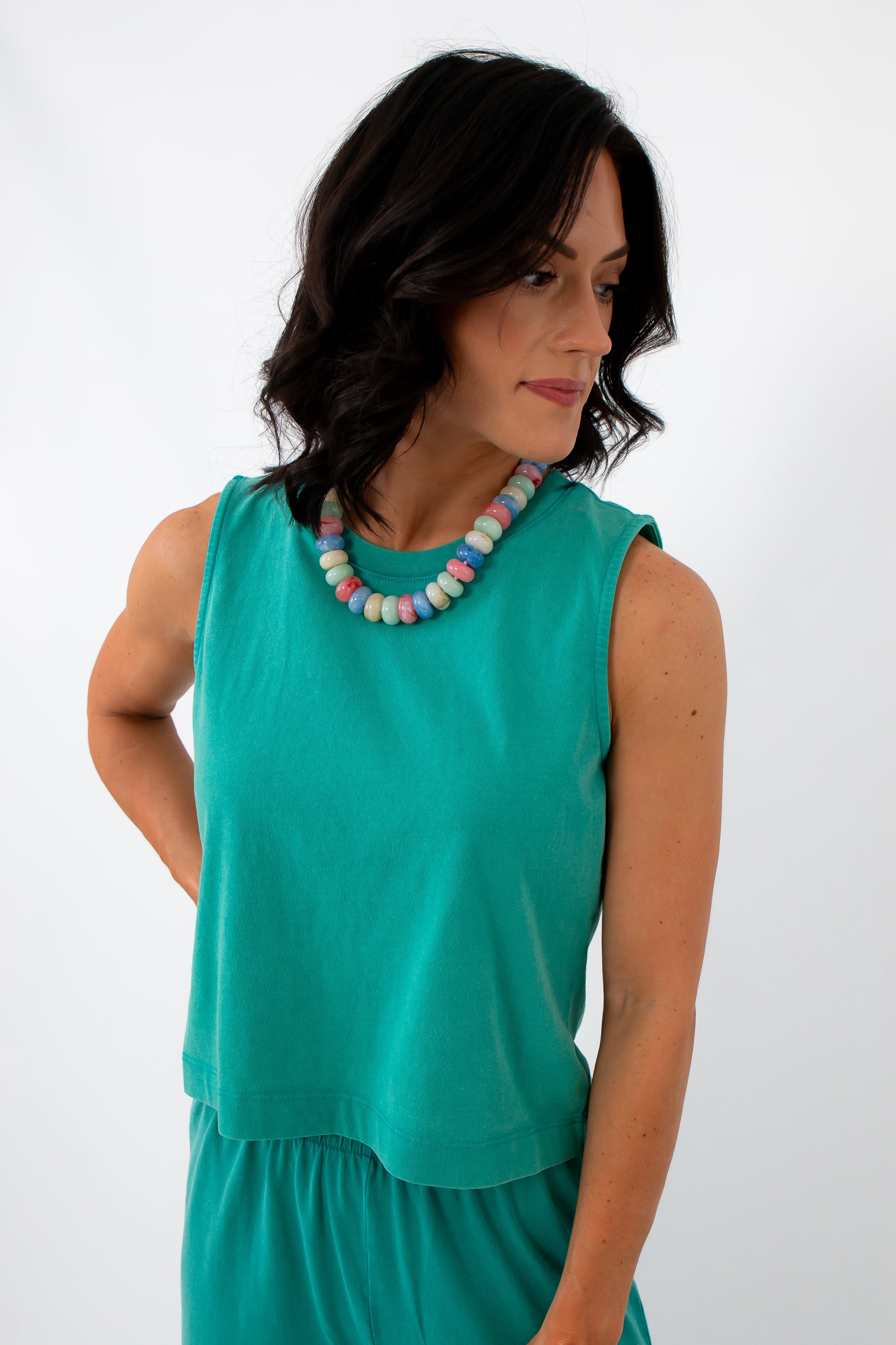Back view of woman in bright teal sleeveless top, casual summer clothing