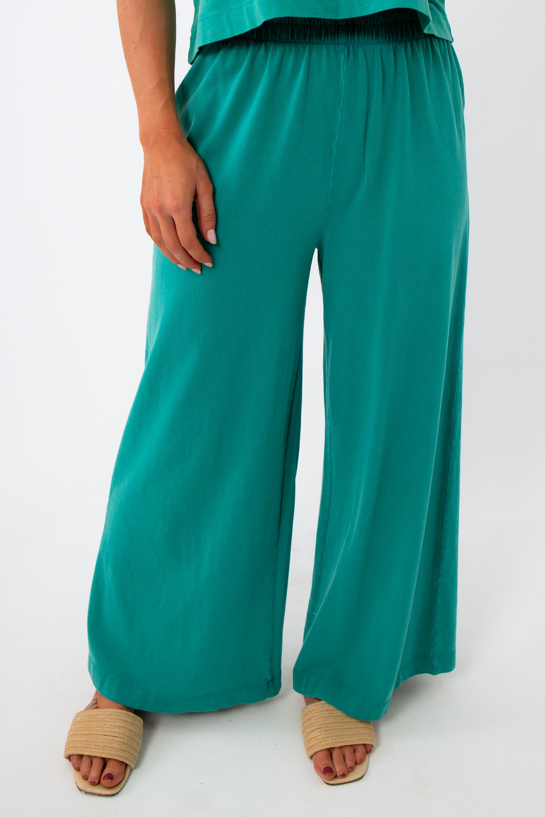 Close-up of teal lounge pants with elastic waistband and wide-leg fit