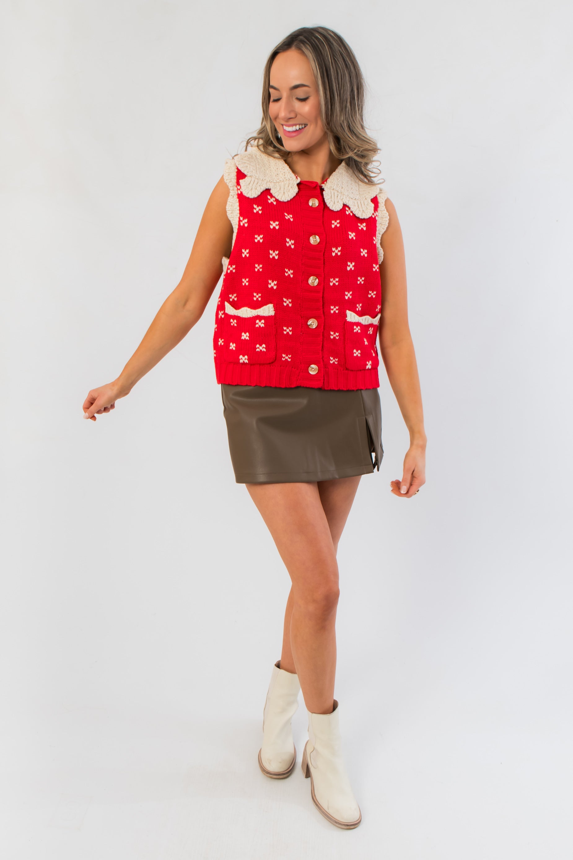 Clara Collared Knit Sweater Vest in red with cream doll collar, styled with olive mini skirt and white ankle boots for festive winter layering.