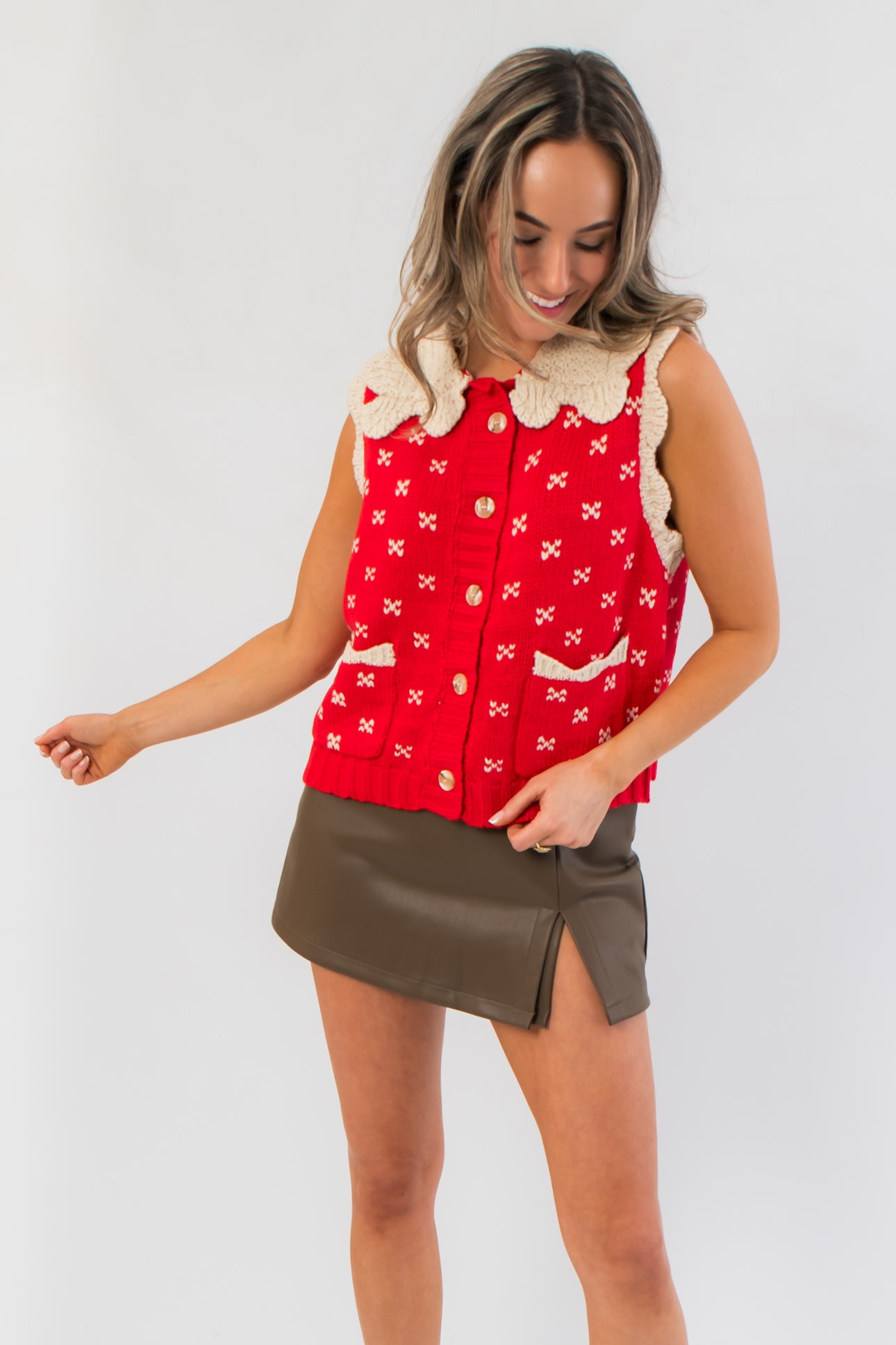 Front view of Clara Collared Knit Sweater Vest featuring red knit fabric with cream bow details and front pockets, ideal for holiday outfits.