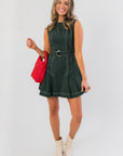 Charlie Belted A-Line Evergreen Mini Dress with contrast stitching, styled with a red handbag and cream ankle boots for a festive holiday look.