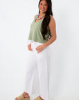 Model wearing white wide-leg denim jeans with green tank top and platform sandals