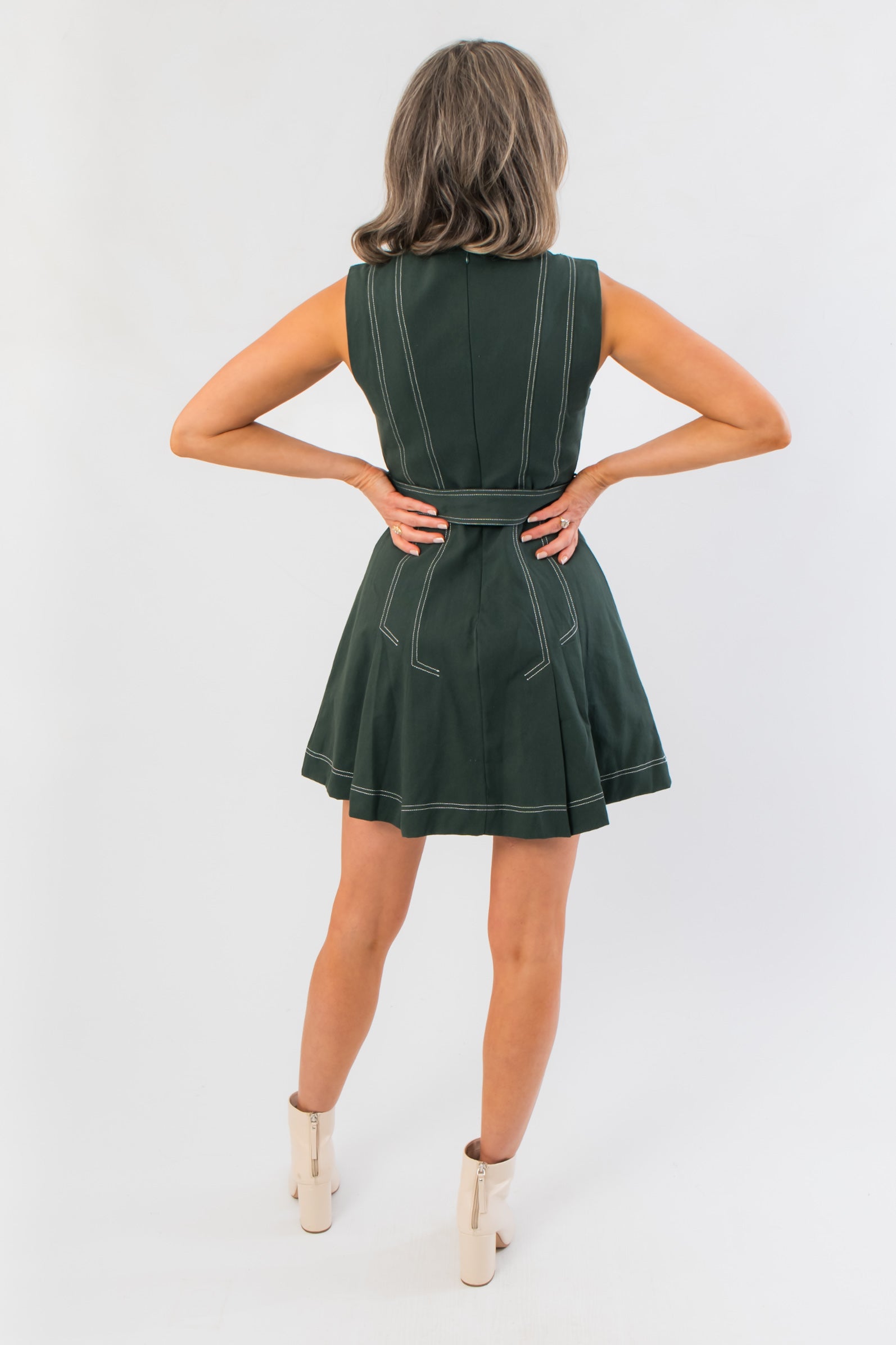 Back view of Charlie Evergreen Mini Dress with belted waist and contrast stitching, highlighting its flattering A-line cut for holiday occasions.