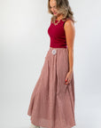 Side view of Wine & Dine Sleeveless Sweater in wine rib knit, styled with a checkered skirt and ankle boots for a cozy fall ensemble.