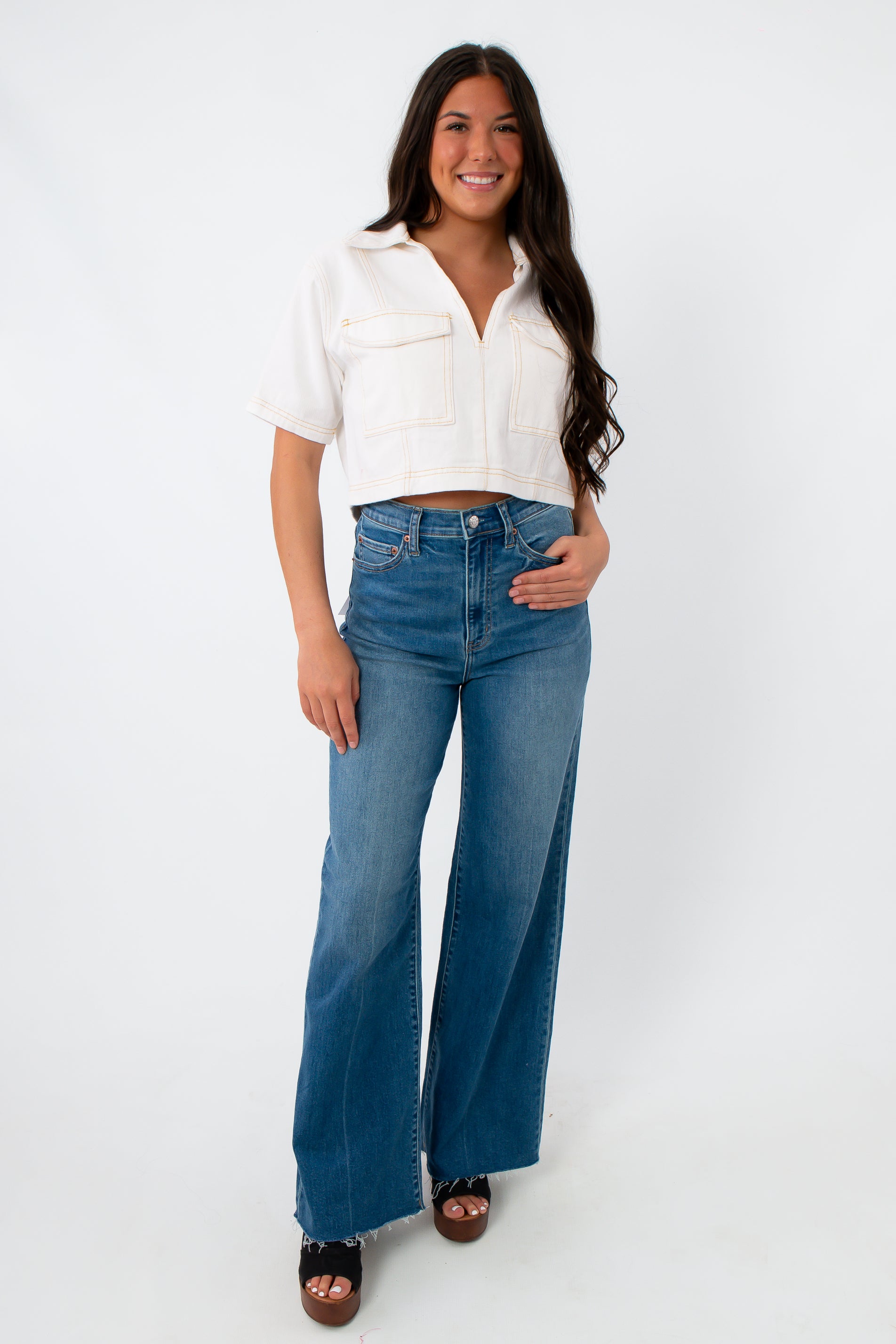 Model wearing white denim contrast stitch short sleeve top with high-waisted jeans