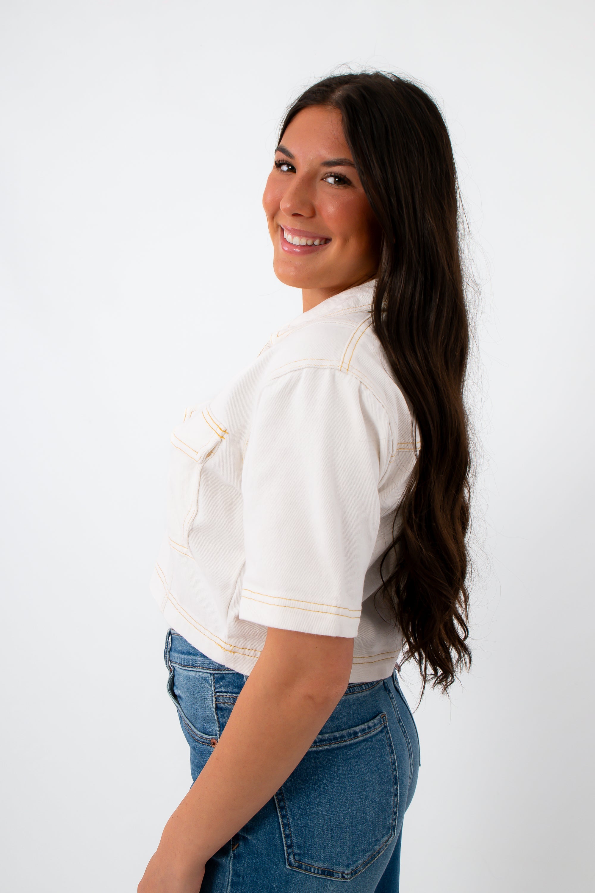 Back view of white denim contrast stitch short sleeve top with model smiling