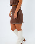 brown linen mini skirt with white stitching details styled for football game