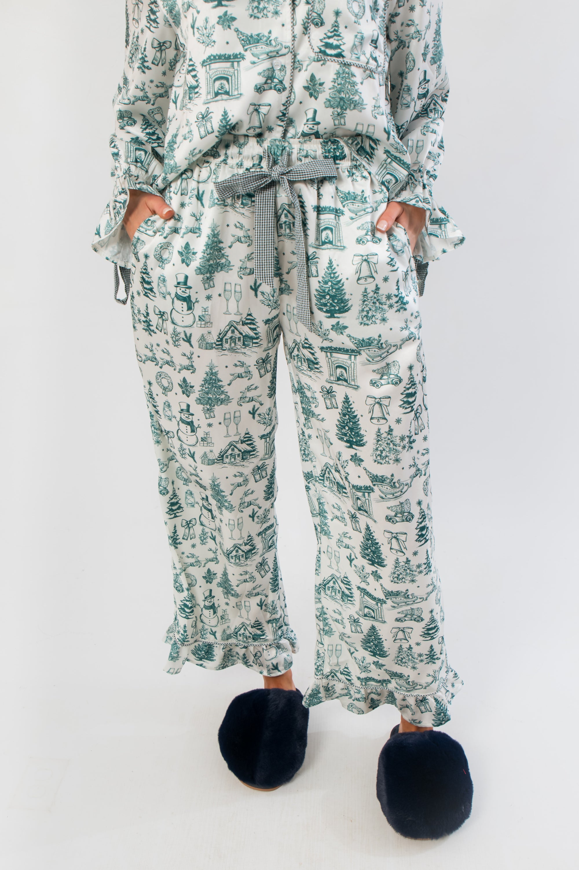 Close-up of Heritage Holiday Toile Green Pajama Set pants with green holiday motifs, ruffle trim, and striped ribbon drawstring for adjustable fit.