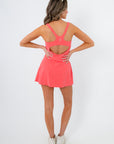Free People Hibiscus Never Better Dress in vibrant coral pink with racerback and cutout detail, ideal for summer athleisure style.