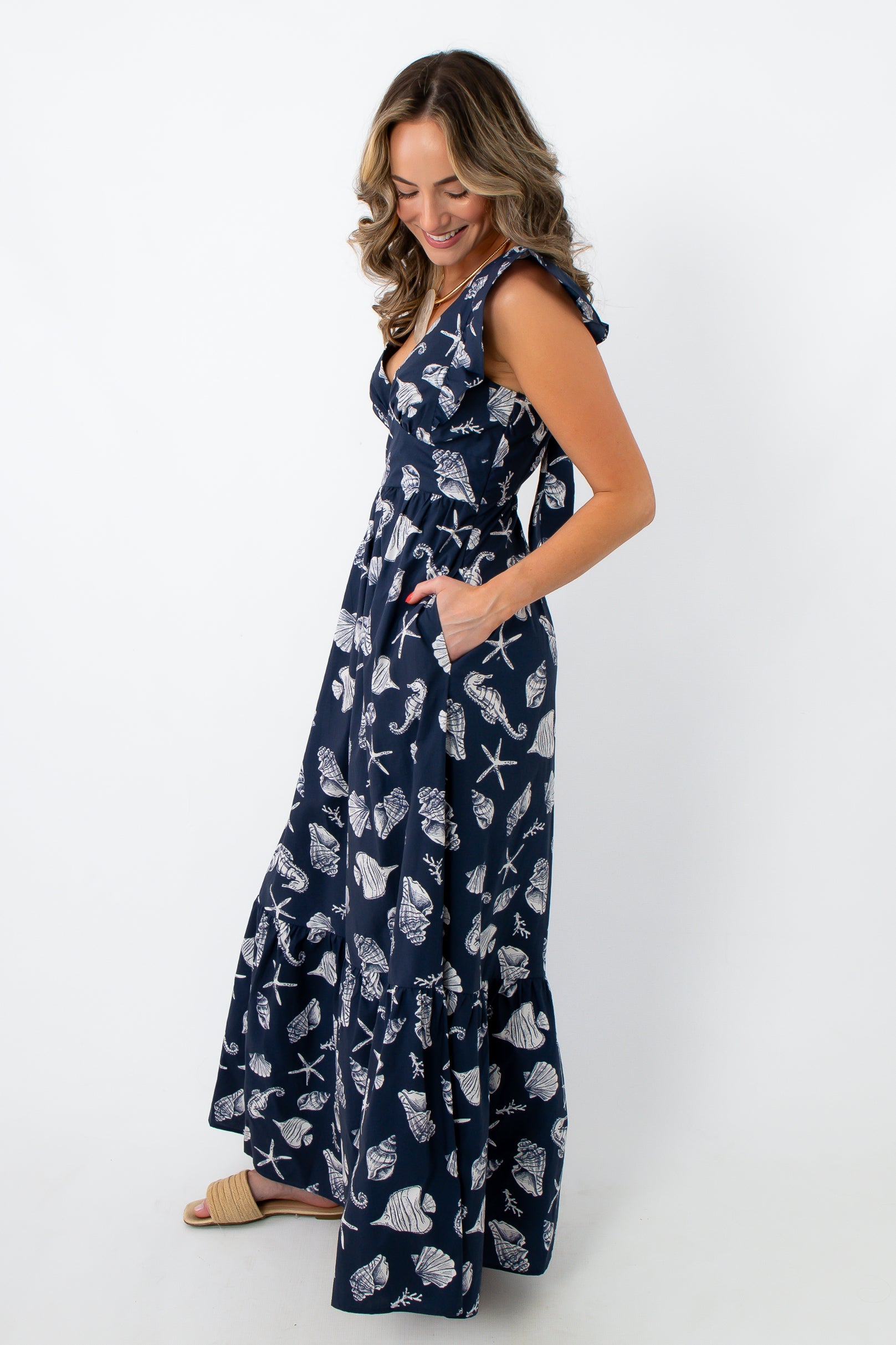 Side view of navy seashell print maxi dress with tie back and ruffle details