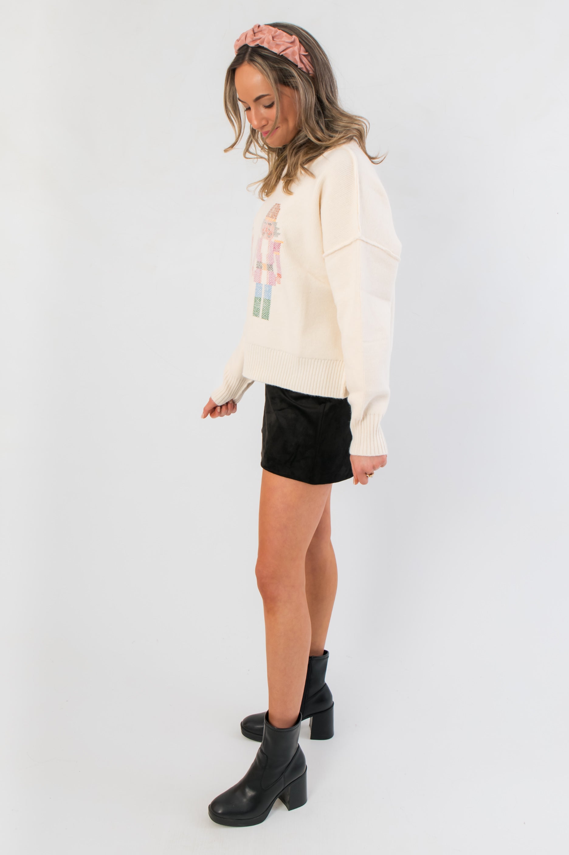 Side view of Twin Tidings Nutcracker Sweater – soft cream knit with festive nutcracker detail, styled for cozy and chic seasonal fashion.
