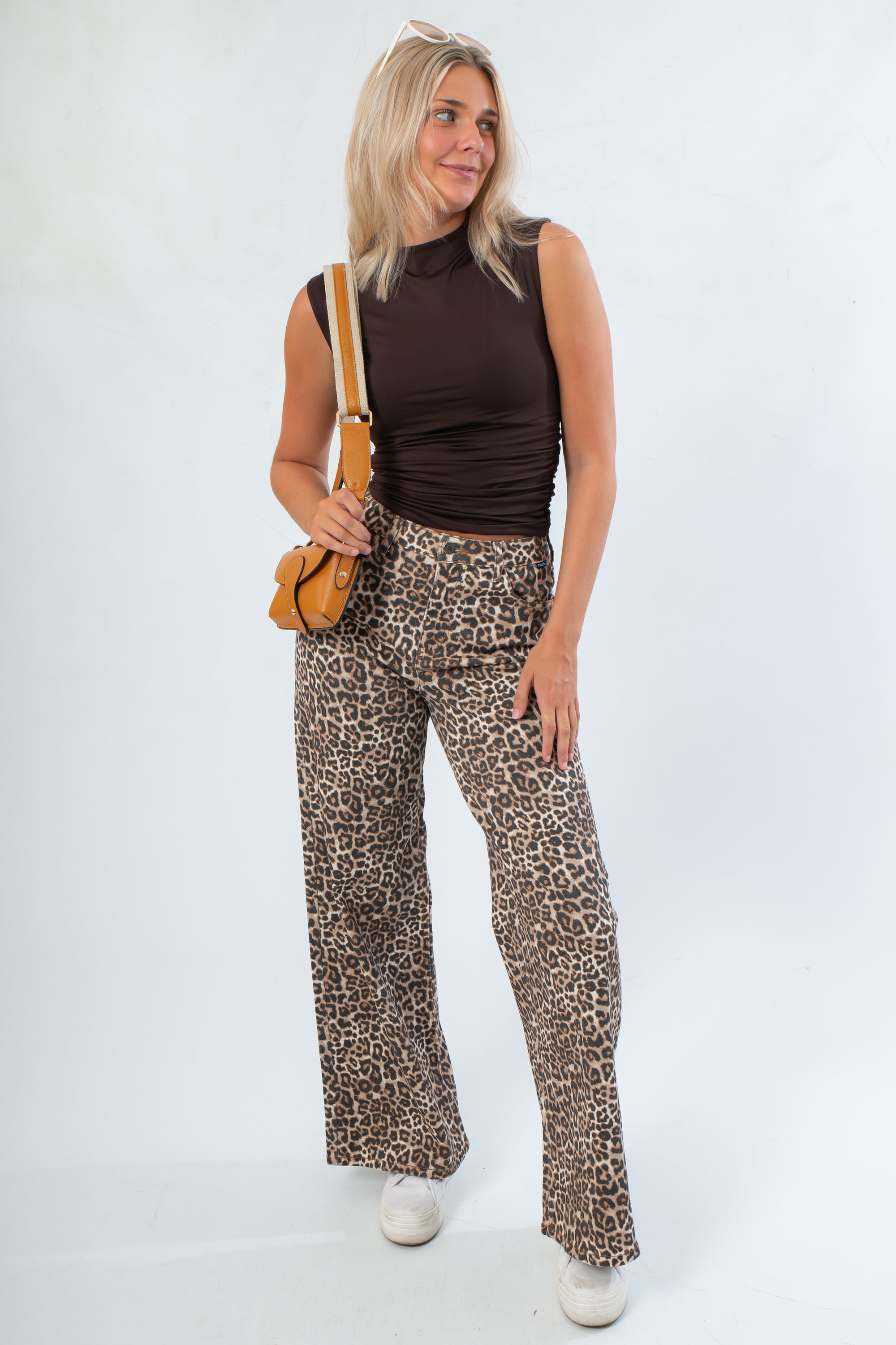 Model wearing Luck Of The Draw Brown Ruched Funnel Neck Tank – Sleek Fit with wide-leg leopard pants, showcasing a chic sleeveless fall look.
