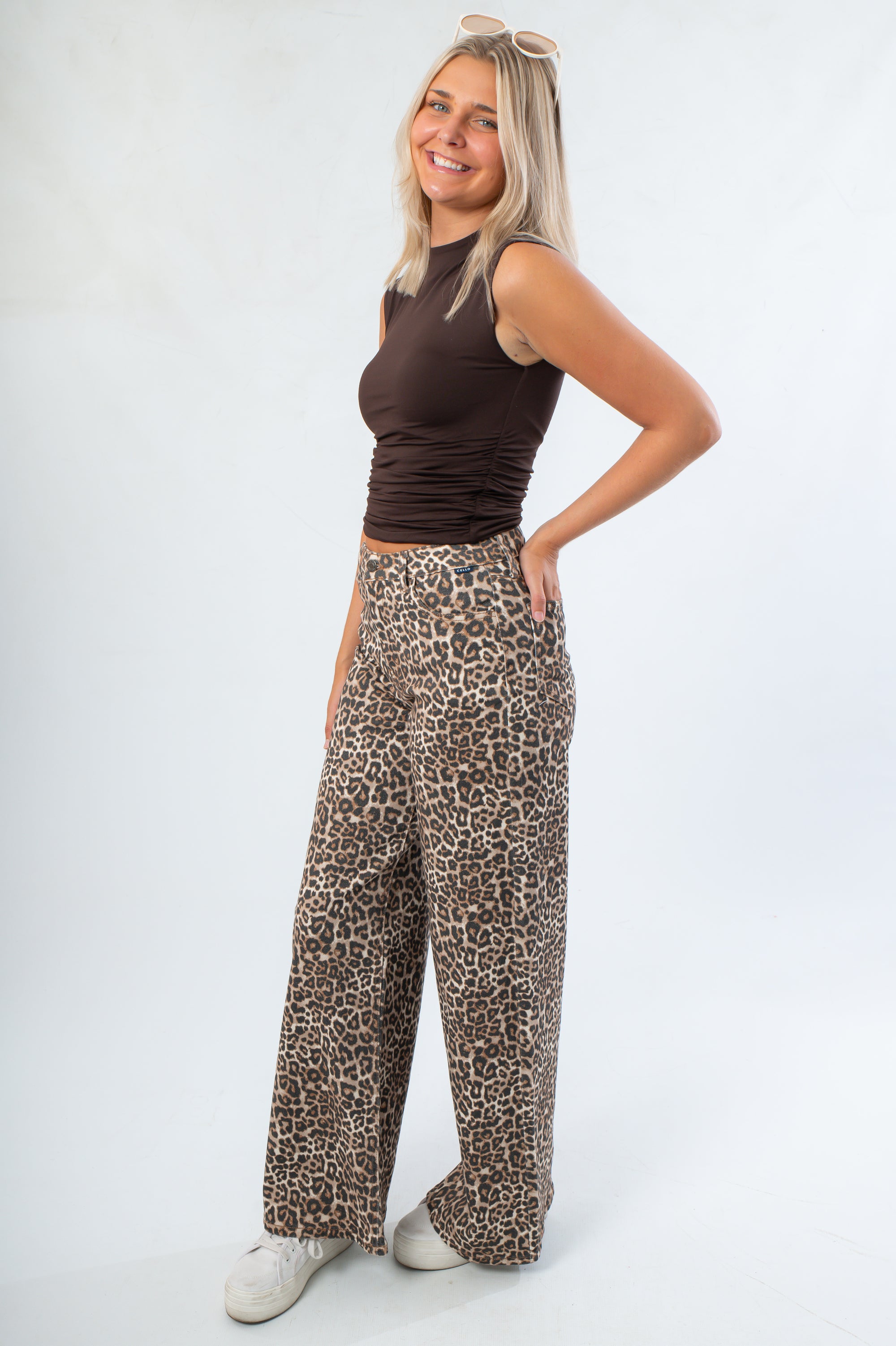 Side view of Luck Of The Draw Brown Ruched Funnel Neck Tank – Sleek Fit paired with leopard print trousers, highlighting the ruched detailing.
