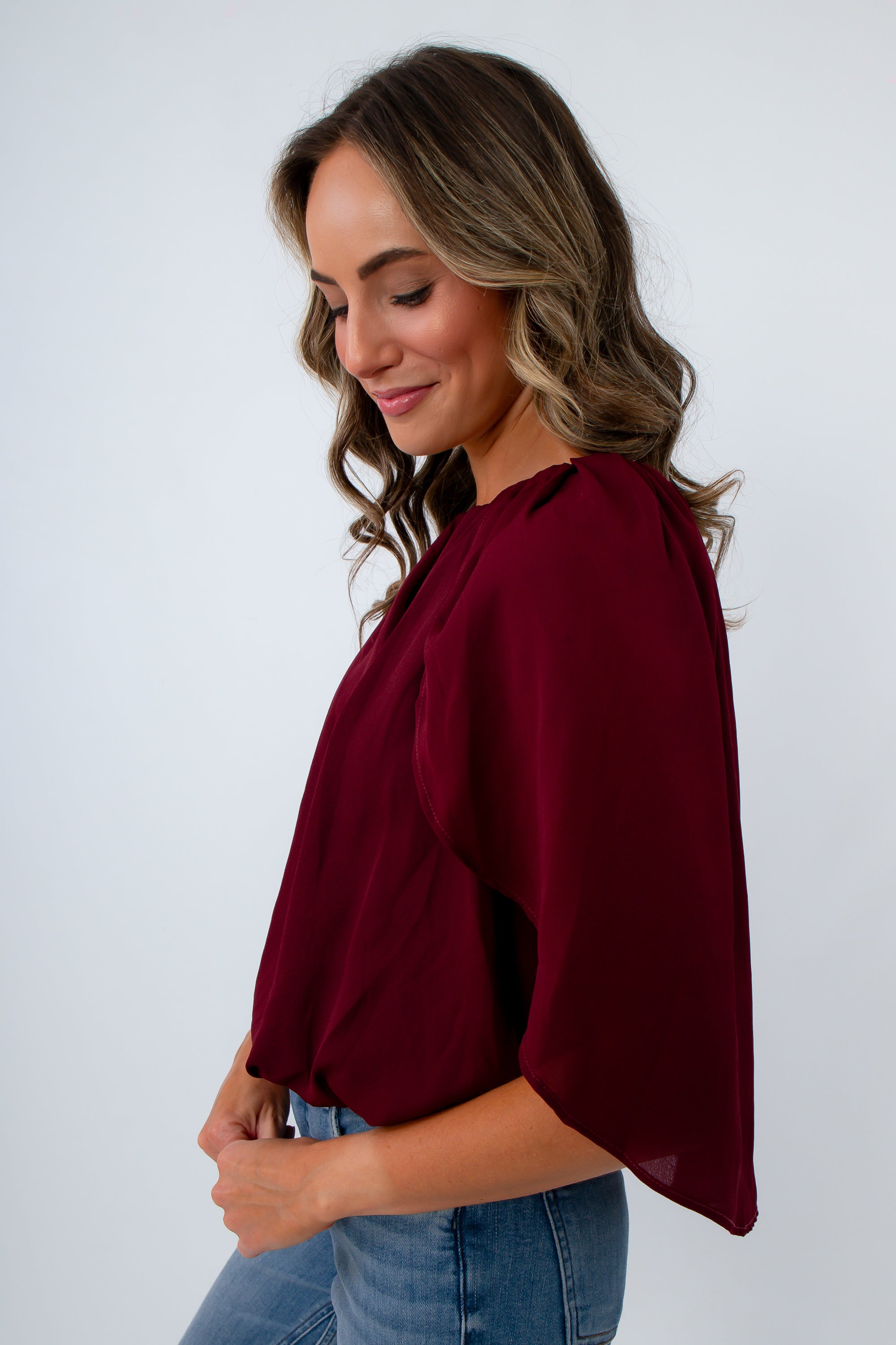 Women’s dressy burgundy top for fall with cape sleeves and a shirred neckline for date night, workwear, and game day
