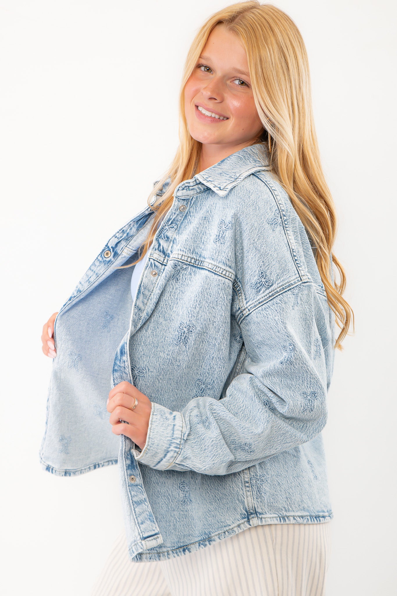 Stylish oversized denim jacket with delicate embroidered bow details, button closure, and drop shoulders for a casual yet chic outerwear option.