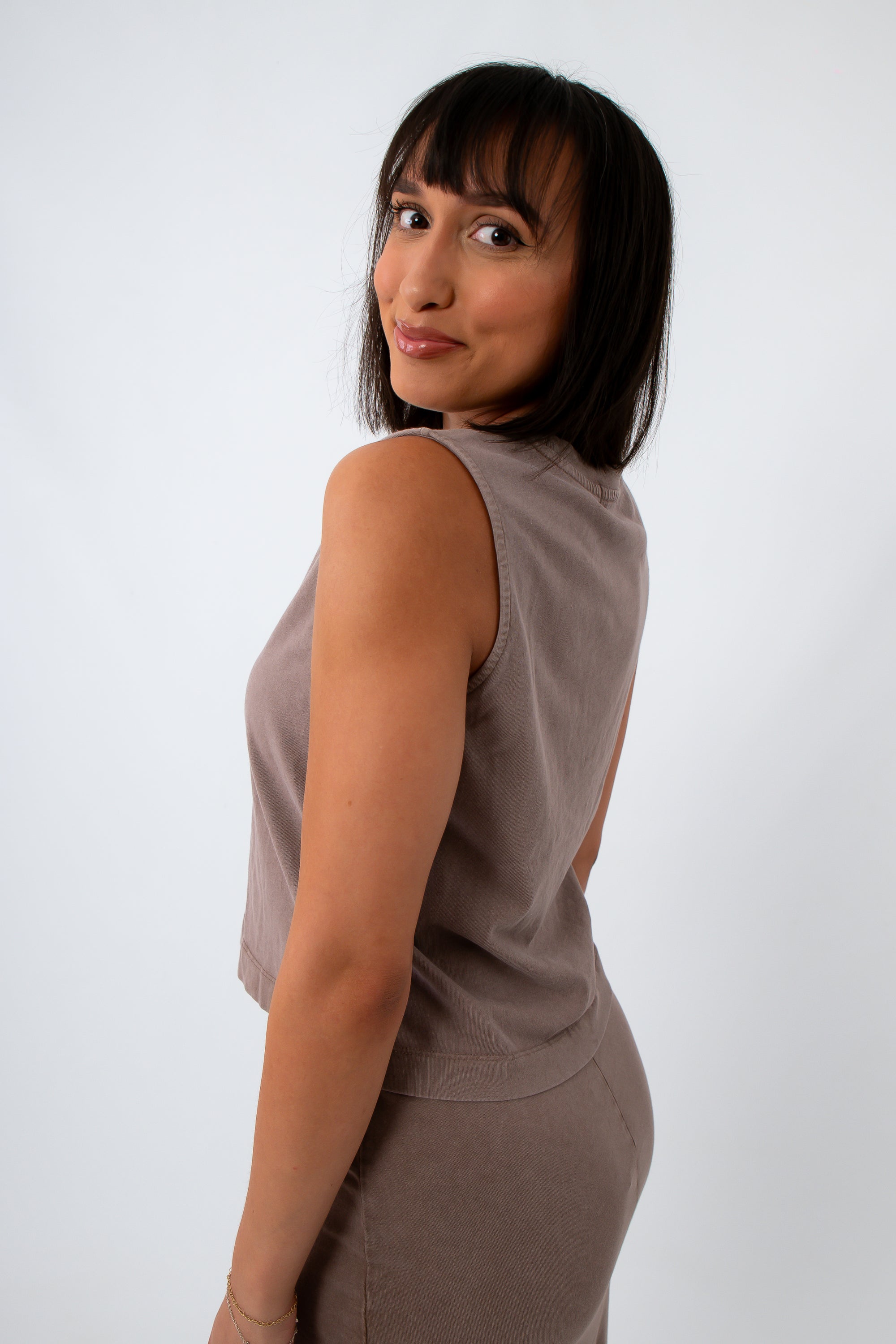 woman in taupe sleeveless tank top, side view with shoulder turned