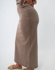Side profile of taupe midi skirt with slit and smooth fabric