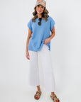 Camila Powder Blue Knit Top styled with white wide-leg pants and sandals, perfect for spring casual wear. Features a relaxed fit and round neckline.