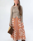 Burnt Orange Floral Patterned Midi Skirt paired with neutral top and woven handbag. A stylish fall outfit for seasonal transitions.