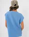 Back view of Camila Powder Blue Knit Top displaying its clean, minimal design and soft knit texture, ideal for spring layering.
