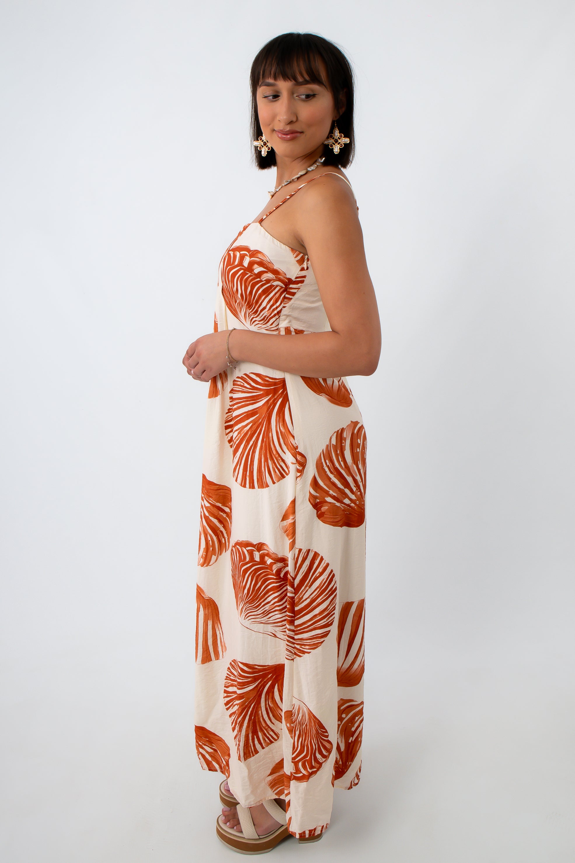 Back view of woman in seashell leaf print maxi dress with shell jewelry