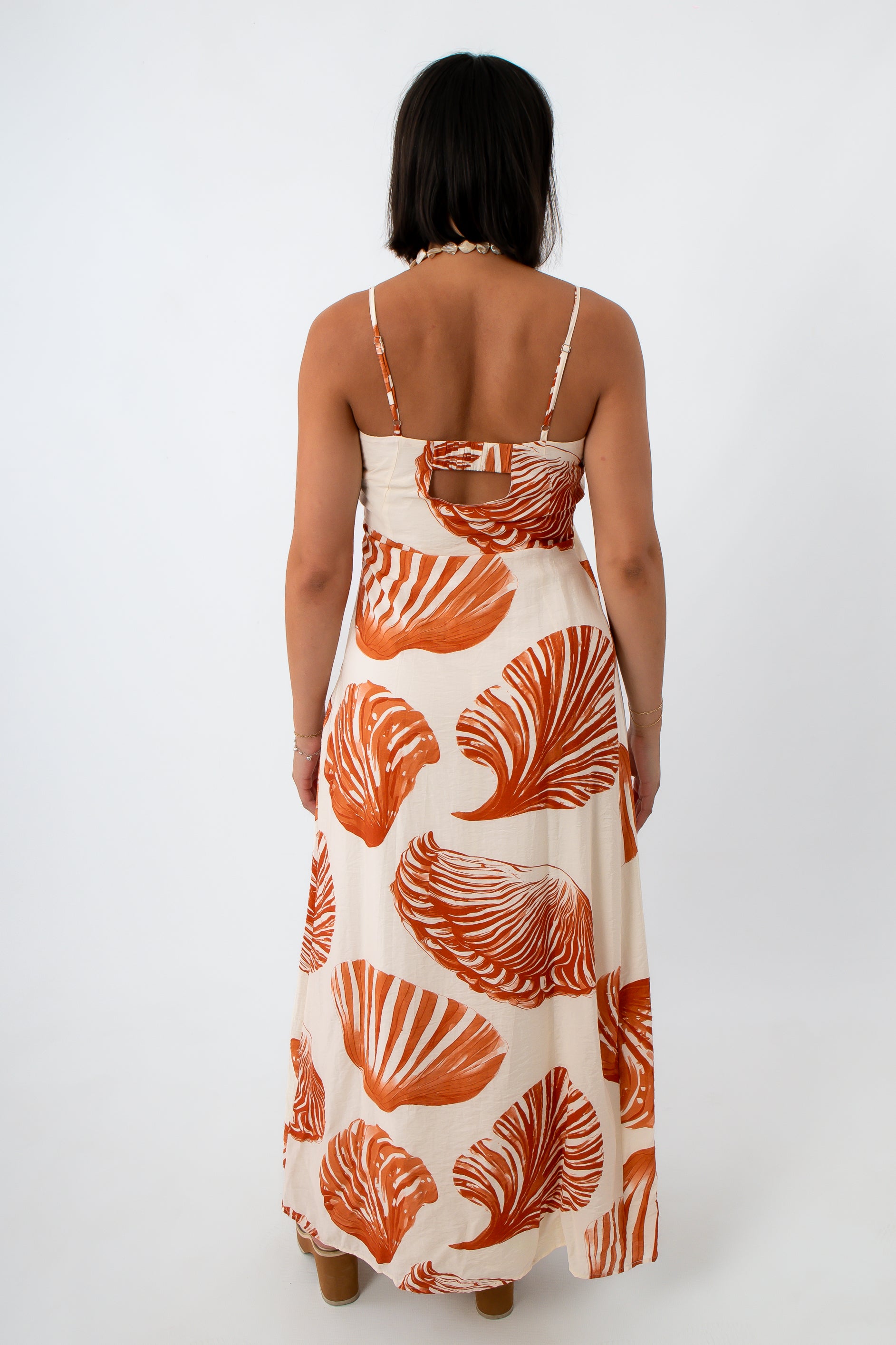Full length of woman in boho seashell print maxi dress with shell jewelry