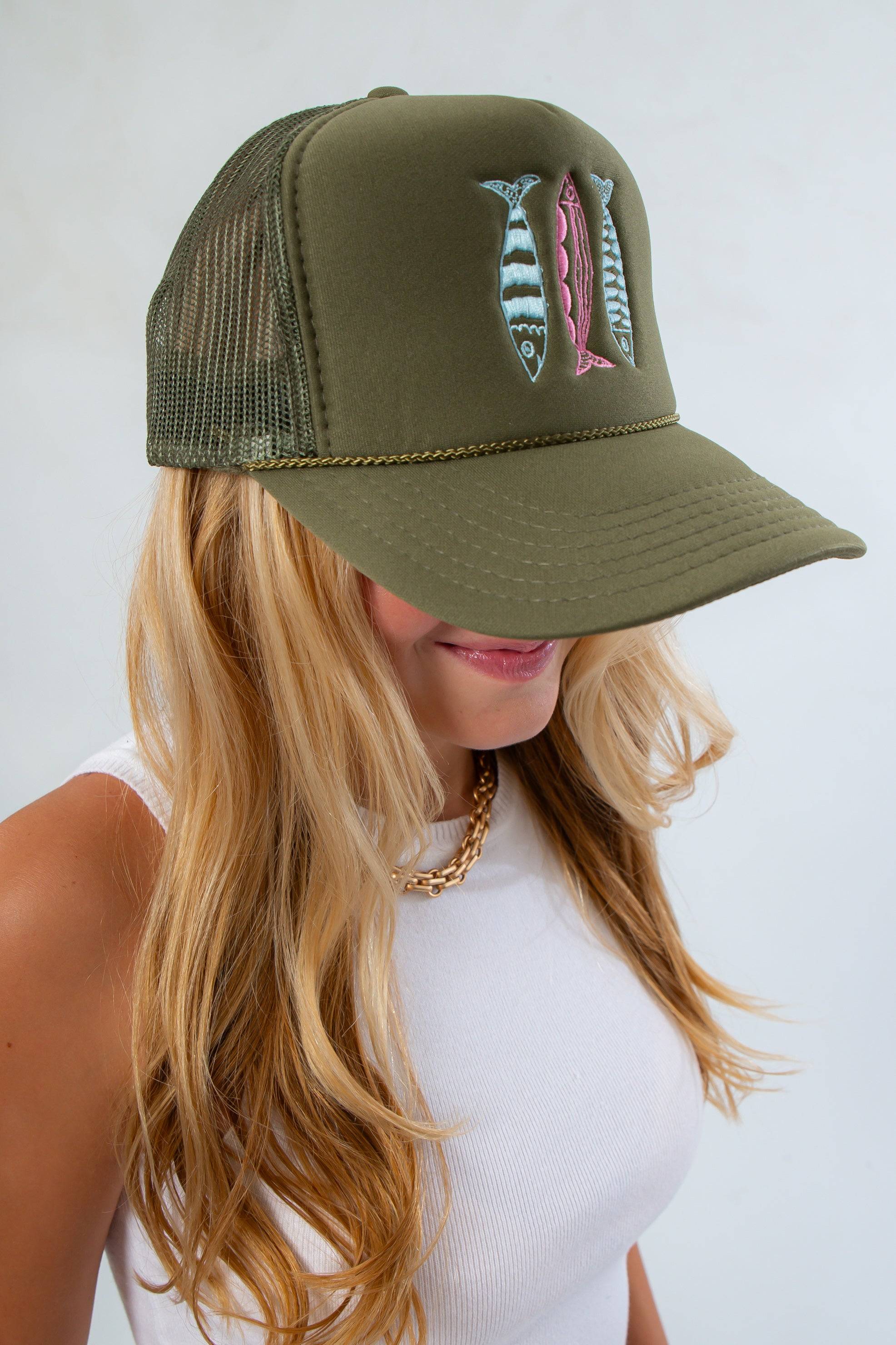 Woman in white tank top modeling Sardines Olive Trucker Hat – Embroidered Snapback for Fall, featuring mesh back and colorful sardine design.