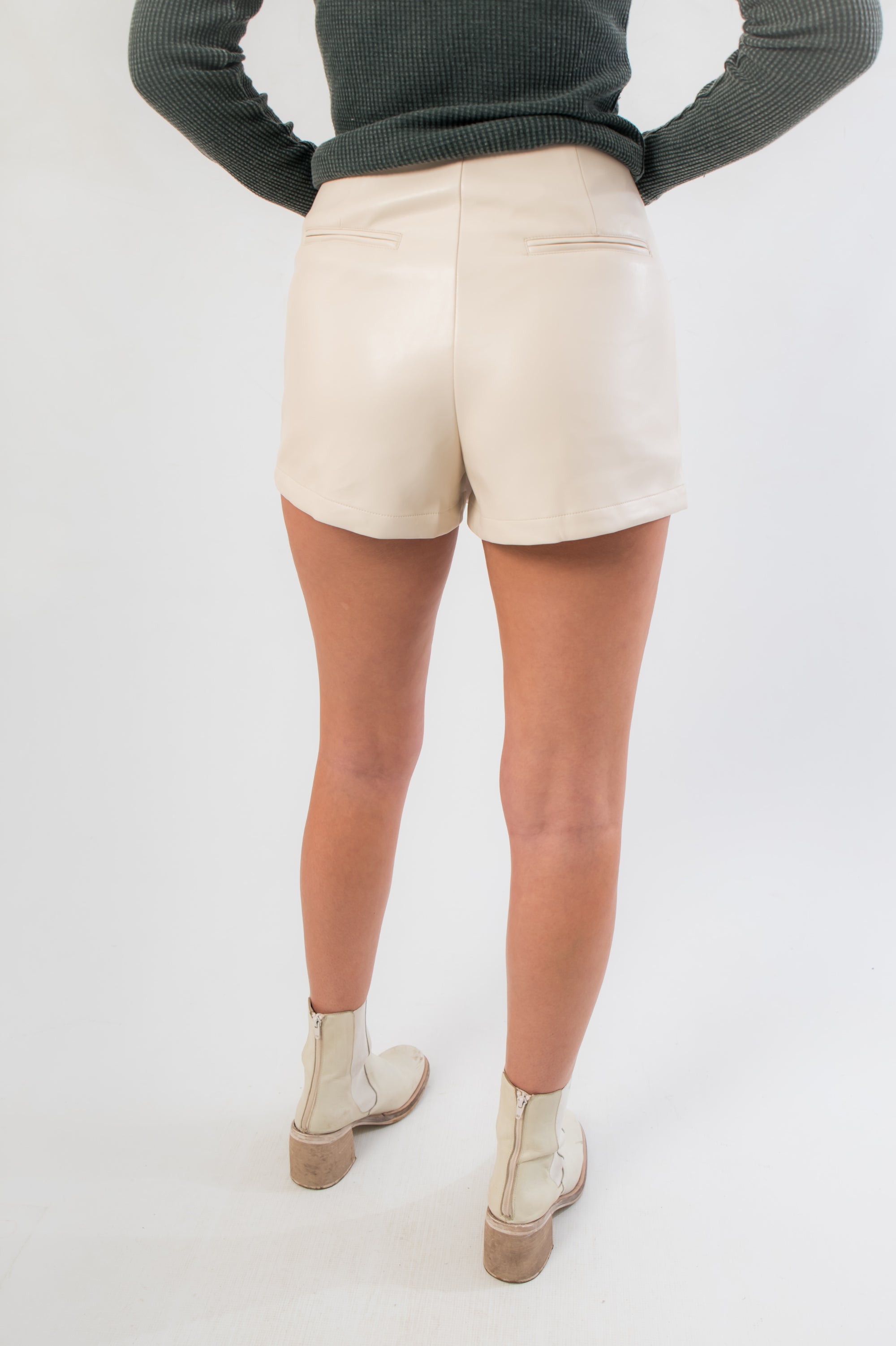 Back view of Falling Back Cream Faux Leather Skort featuring built-in shorts and faux pocket details for comfort and coverage.