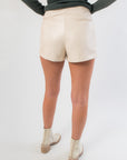 Back view of Falling Back Cream Faux Leather Skort featuring built-in shorts and faux pocket details for comfort and coverage.