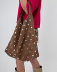 Model holding brown studded slouchy shoulder bag with pink top