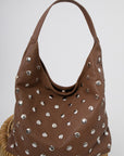 Brown studded slouchy shoulder bag on a wicker chair