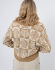 Back view of Cowrie Cutie Seashell Cardigan featuring all-over ivory seashell design on taupe knit, ideal for spring and summer outfits.
