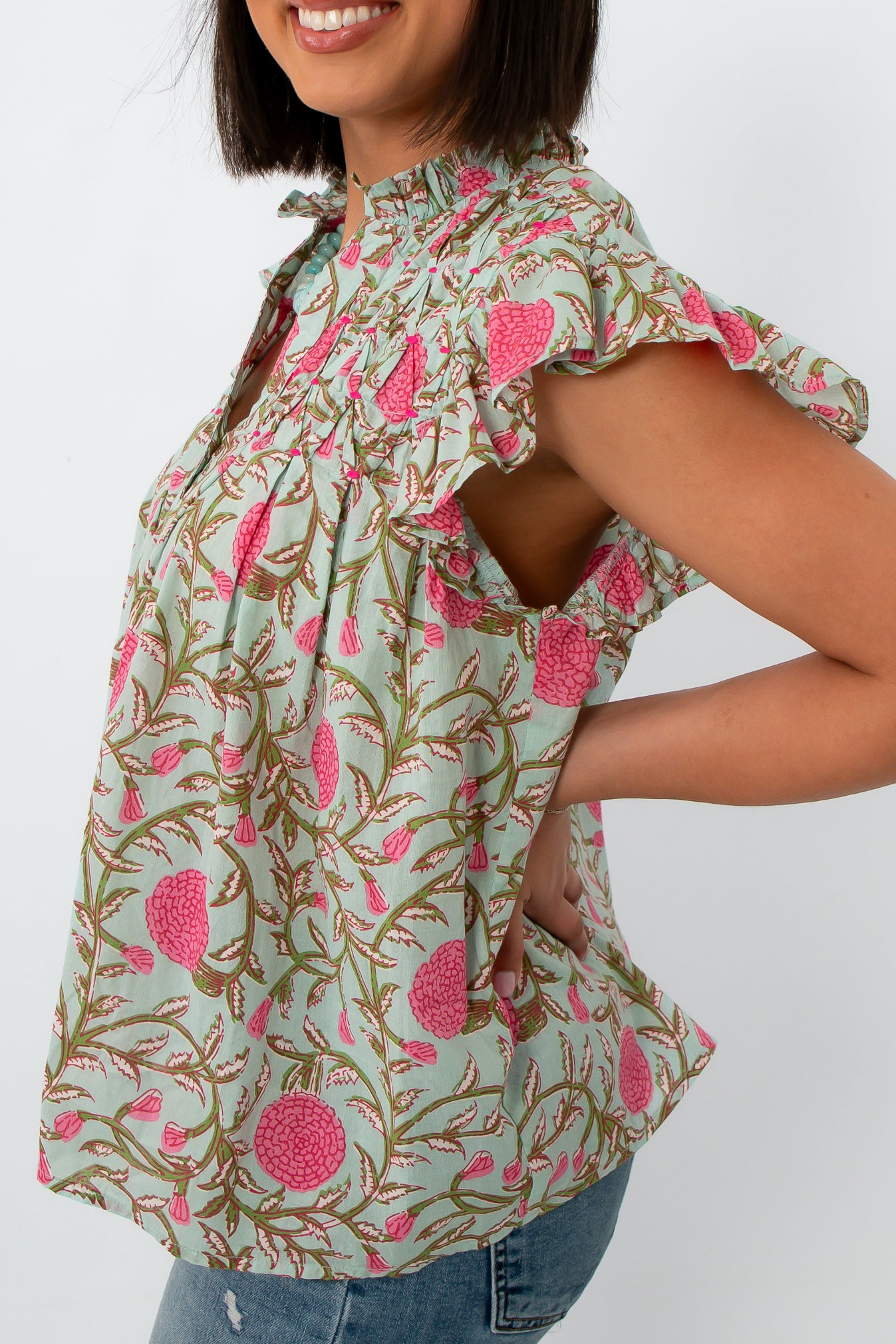 Back view of woman in mint floral flutter sleeve blouse with ruffled shoulders