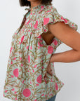 Back view of woman in mint floral flutter sleeve blouse with ruffled shoulders