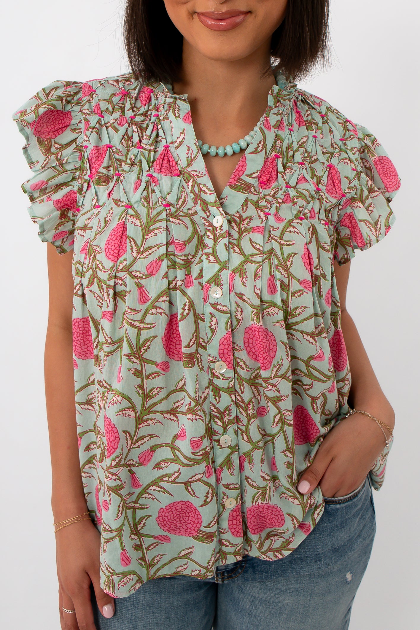 Close-up of woman in mint floral blouse with ruffled sleeves and button details