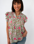 Woman wearing mint floral flutter sleeve blouse with ruffled shoulders and button front