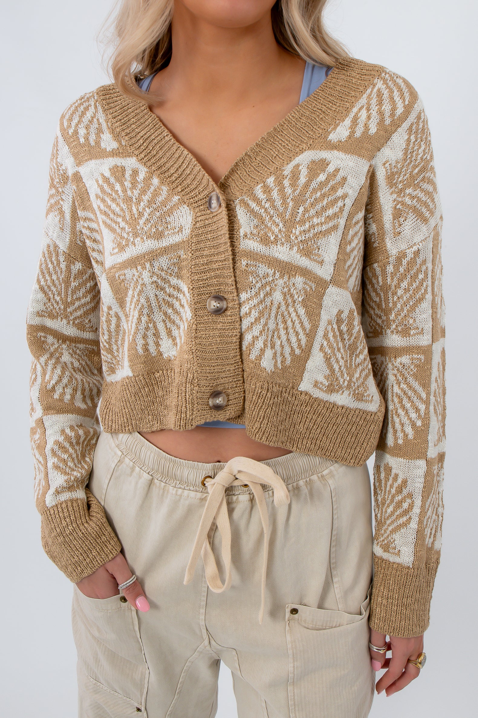 Cowrie Cutie Seashell Cardigan in taupe and ivory with seashell knit pattern, cropped fit, and button front, styled with neutral drawstring pants.