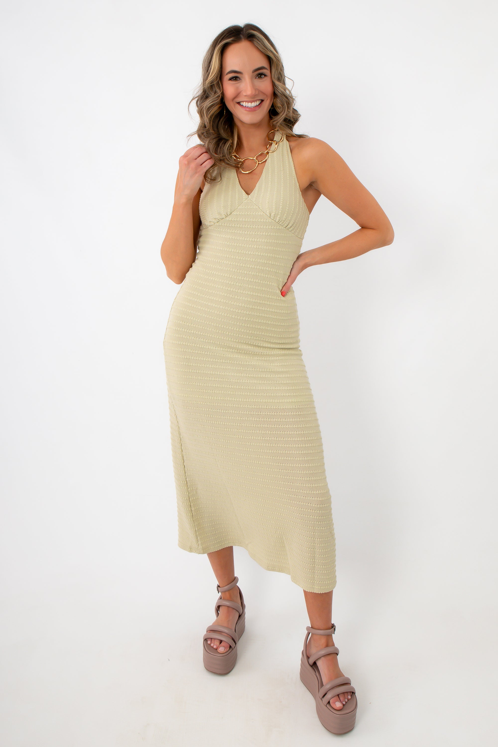 woman in beige textured halter midi dress with chunky platform sandals and gold jewelry