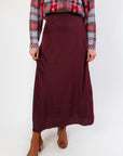 Z Supply Merlot Northpointe Satin Midi Skirt in a rich burgundy hue, styled with a plaid sweater and ankle boots for a chic seasonal look.