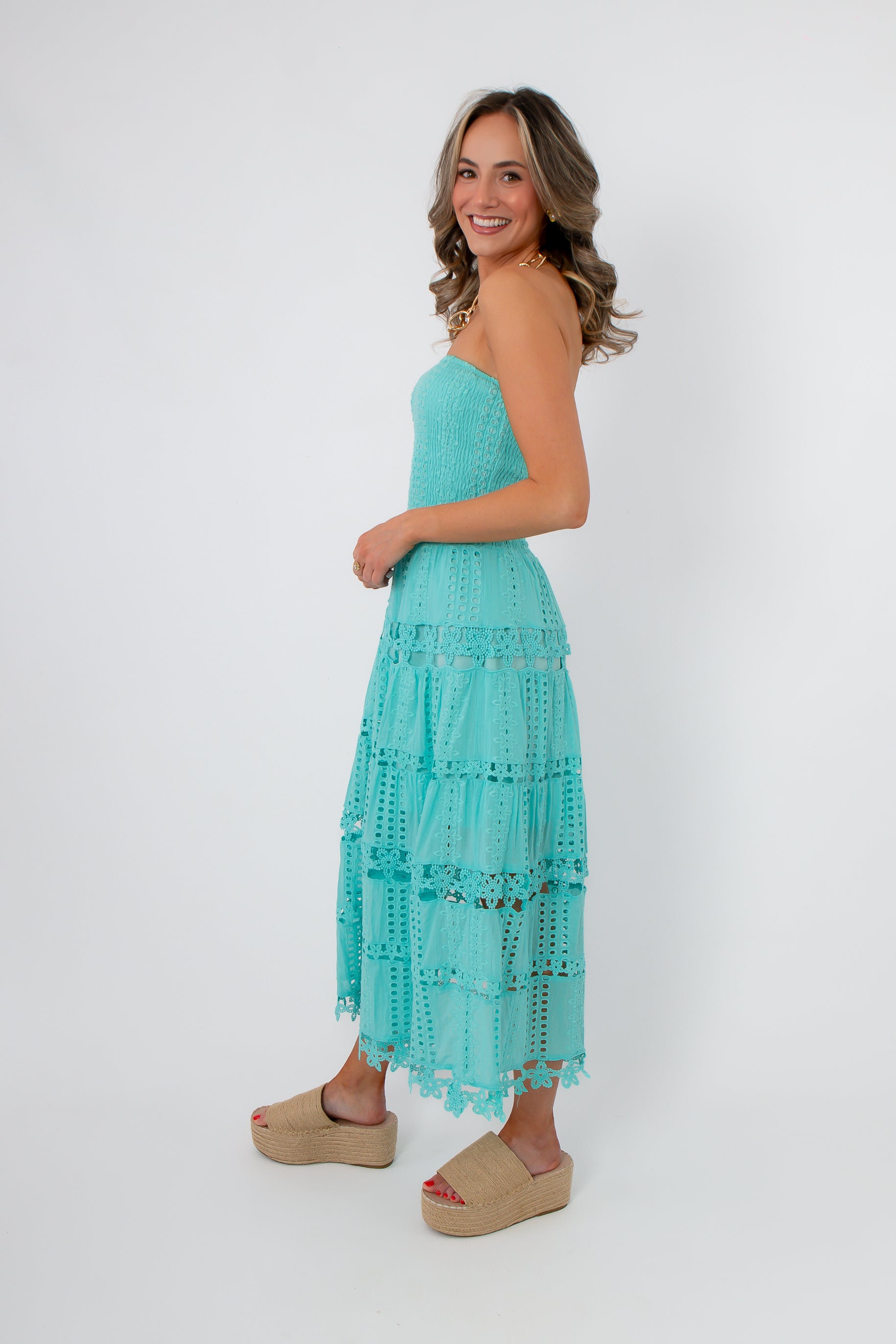 Side view of Aquamarine Moment Eyelet Lace Strapless Dress showing smocked top and flowy tiered lace design in bright Tiffany blue.