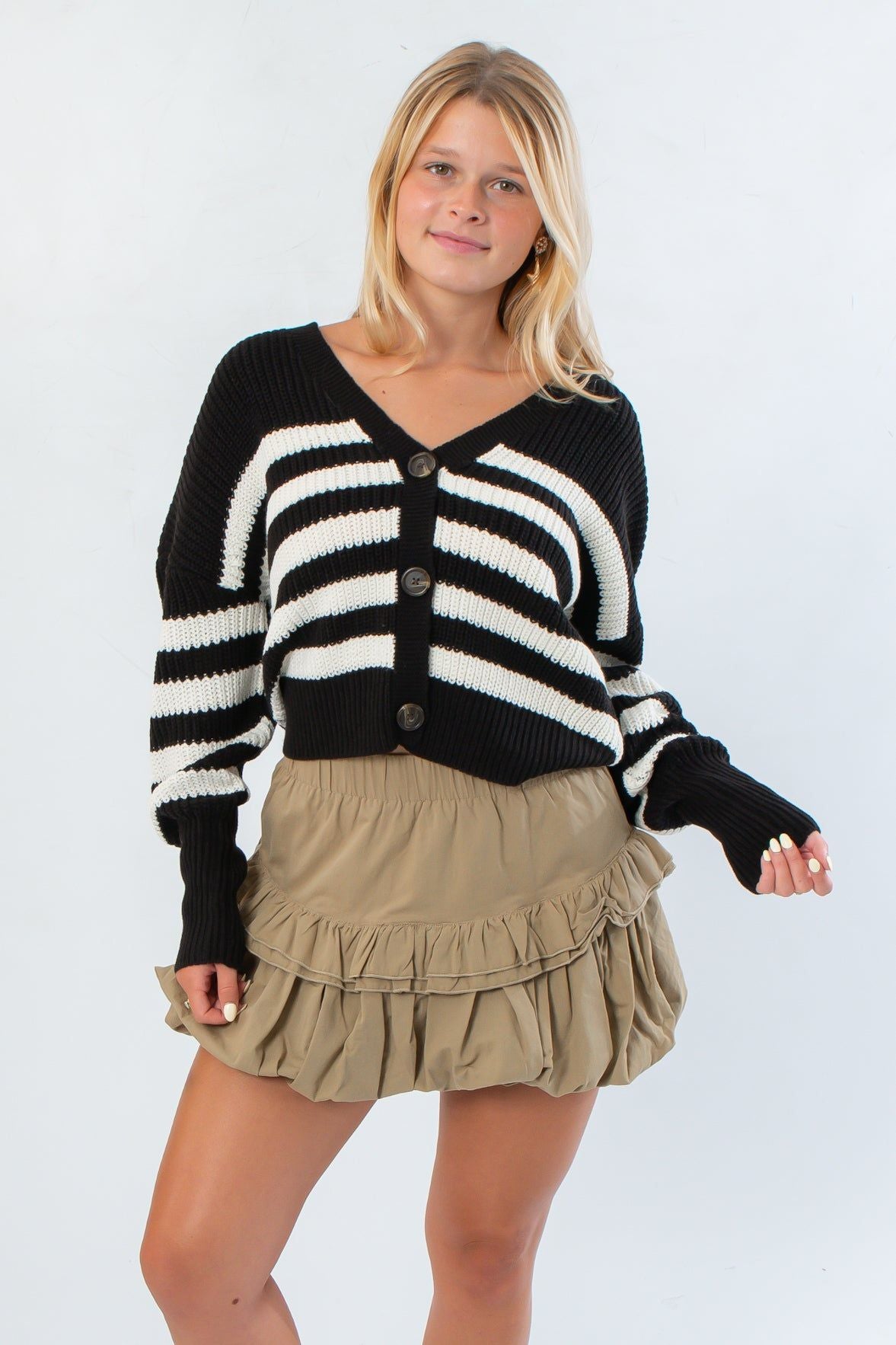 VM Cardigan in Black and White Stripe with oversized buttons and drop shoulder fit, styled with a khaki ruffle mini skirt for a chic fall look.