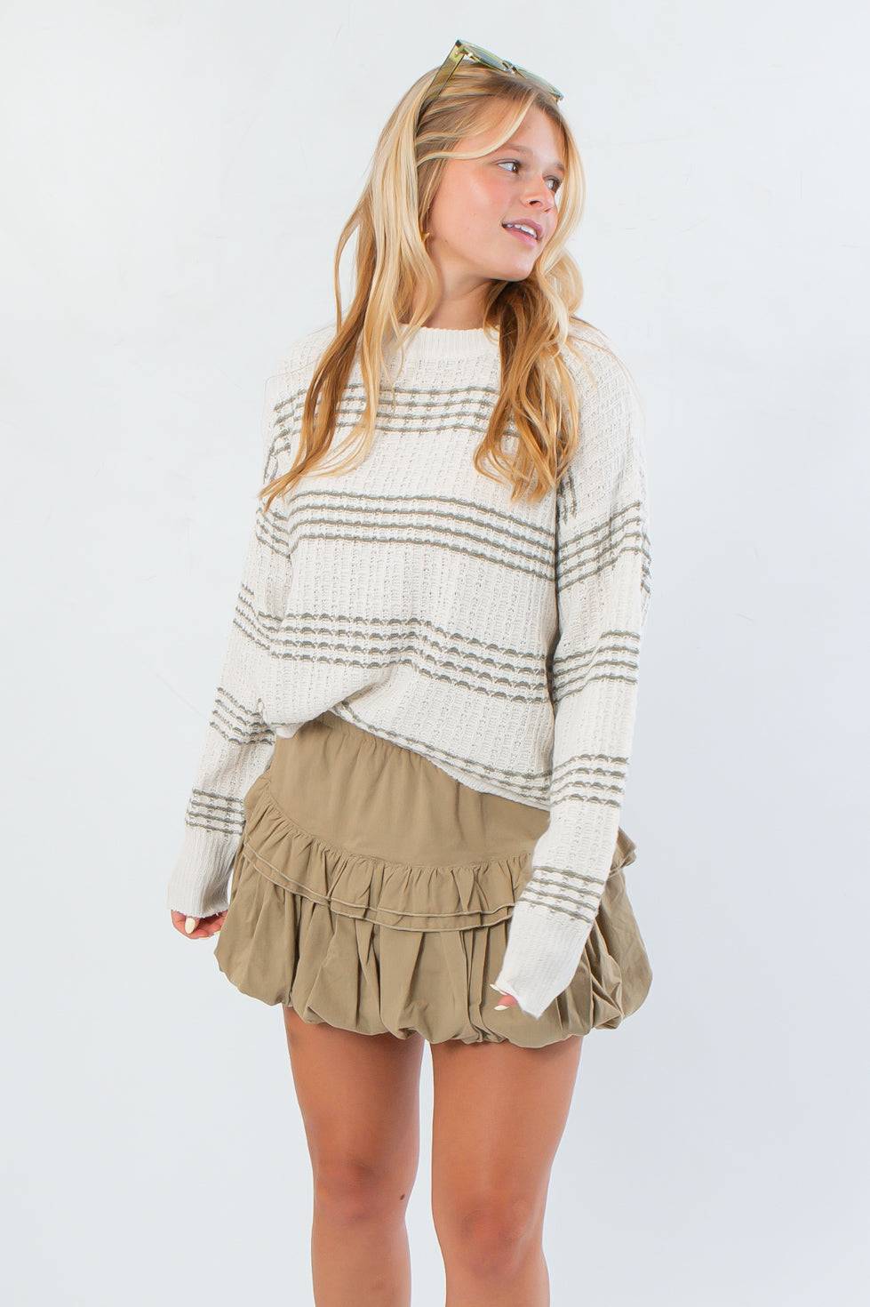 Paige Olive Stripe Textured Sweater with cozy knit and neutral olive stripes, styled with a khaki ruffle skirt for a chic fall look.