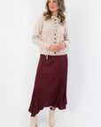 Juniper Multi Color Button Sweater – Stylish beige cardigan with vibrant buttons and tie details, paired with a burgundy midi skirt and ankle boots.