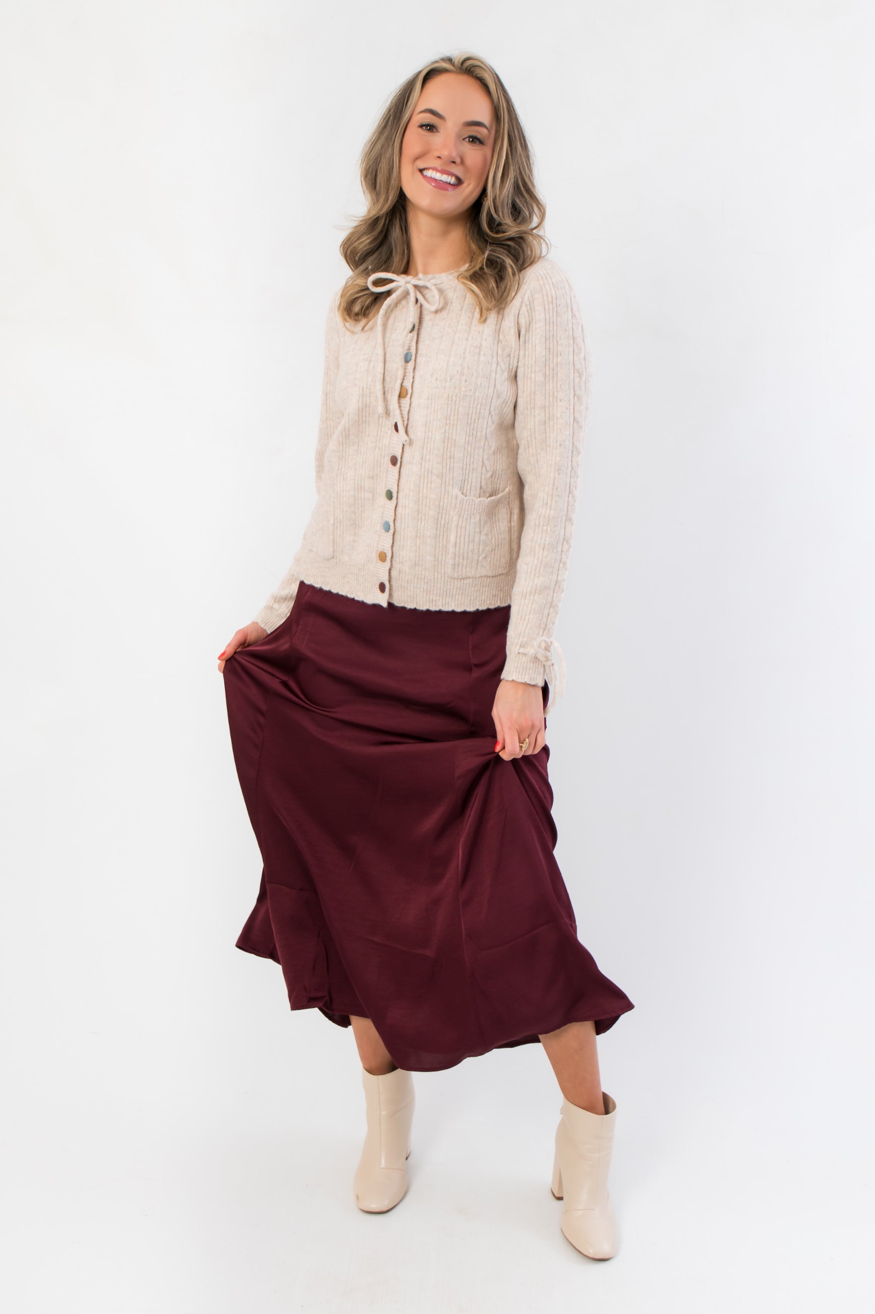 Juniper Multi Color Button Sweater – Cozy beige knit sweater with multicolor buttons and tie cuffs, styled with a flowy burgundy skirt for fall fashion.