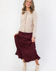 Juniper Multi Color Button Sweater – Cozy beige knit sweater with multicolor buttons and tie cuffs, styled with a flowy burgundy skirt for fall fashion.