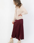 Juniper Multi Color Button Sweater – Side view of beige cardigan with ribbed texture and colorful buttons, styled with a burgundy skirt and cream boots.