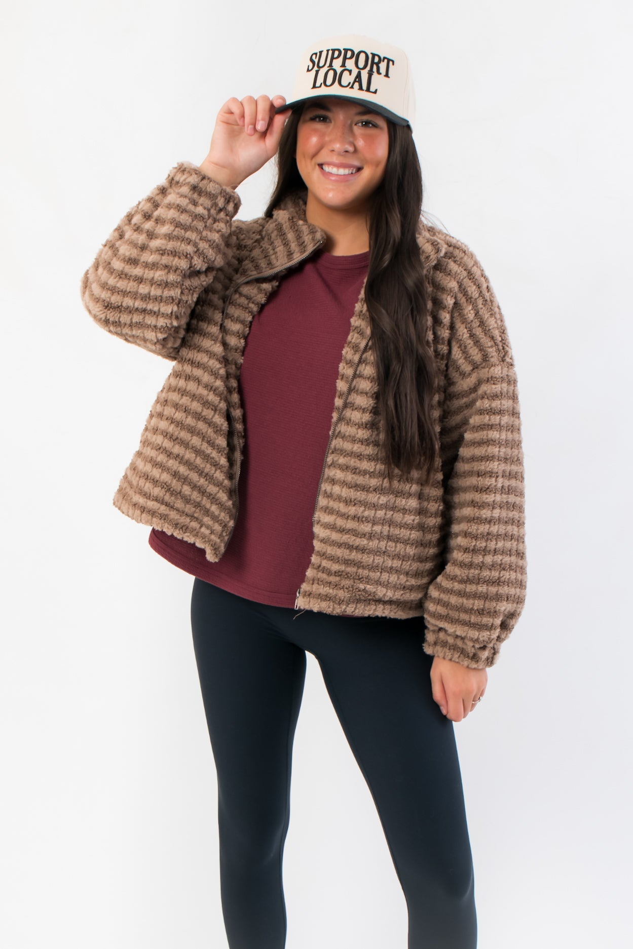 Mocha Stripe Front Zip Jacket in fuzzy brown fabric with front zipper and collar, styled with black leggings and a 'Support Local' cap.