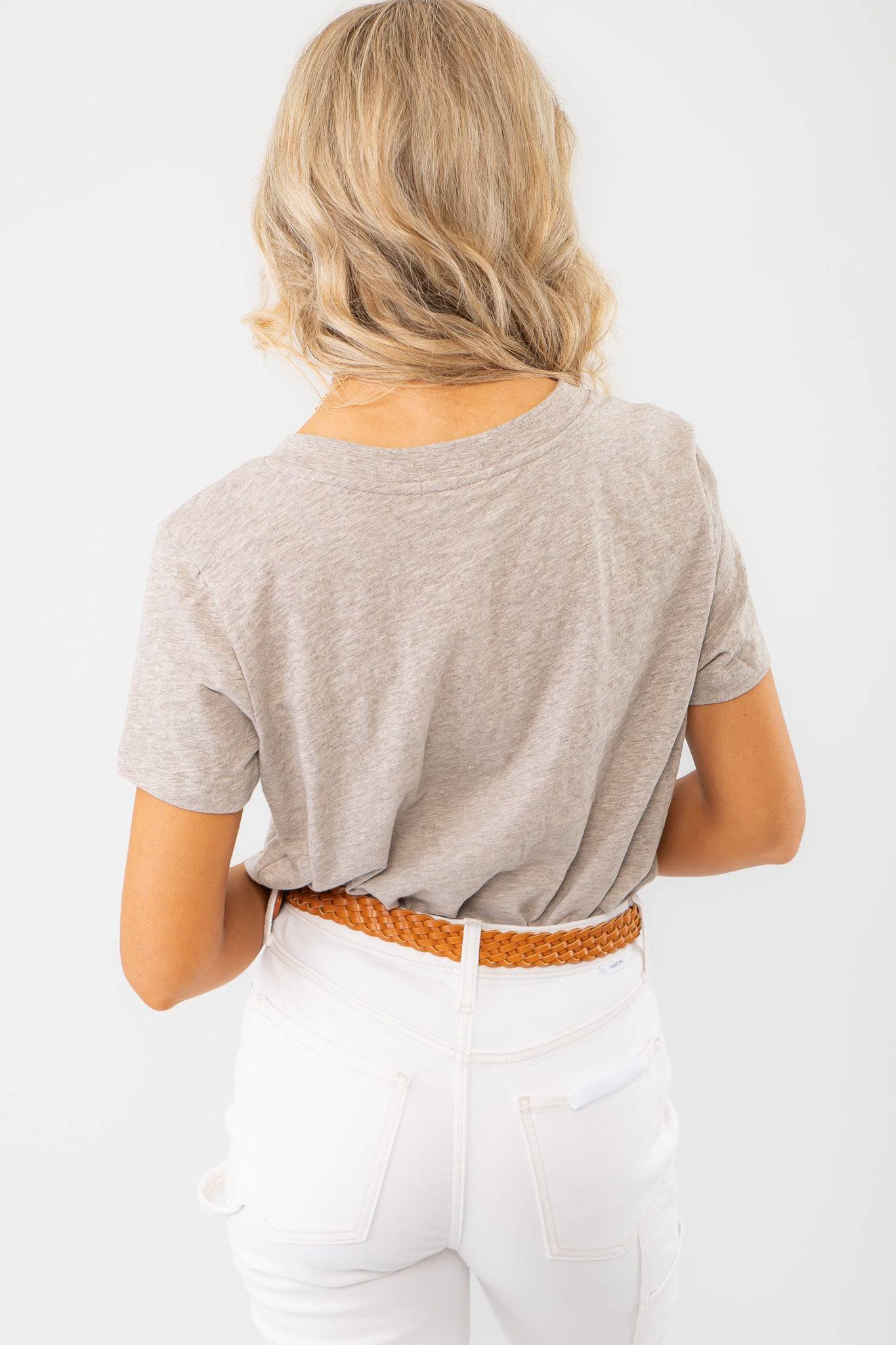 Rear view of the Z Supply Heather Taupe Asher V-Neck Tee, showcasing its soft fabric and relaxed fit, styled with a woven belt and white jeans.